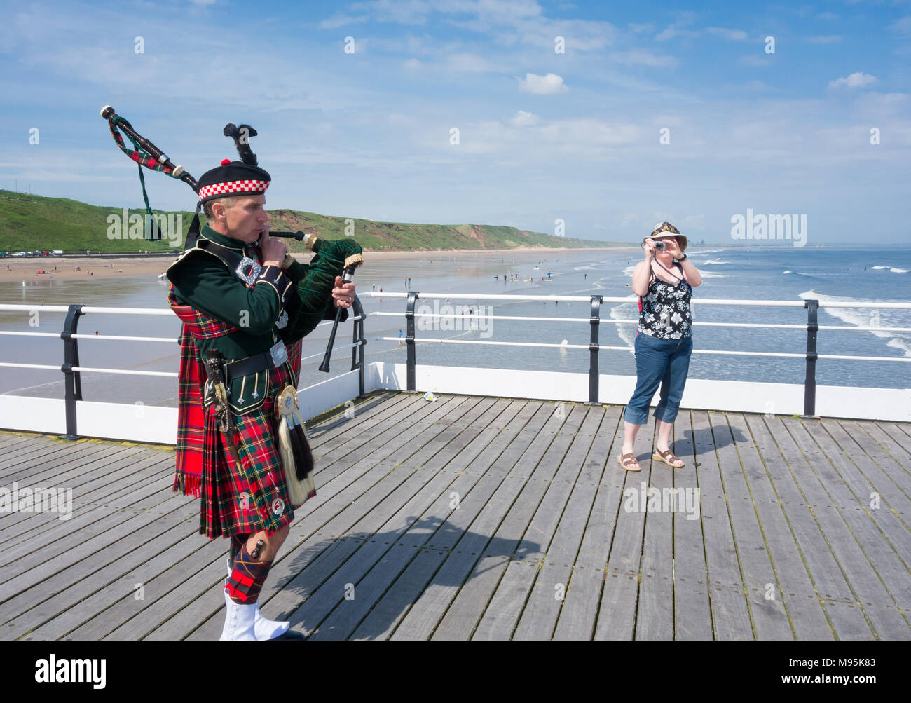 Scottish Piper in traditional dress on Saltburn`s Victorian pier. Saltburn by the sea, North Yorkshire, England, United Kingdom. Stock Photo